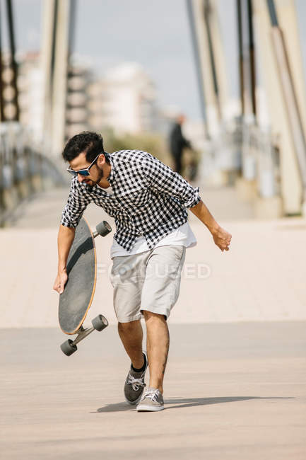 Hombre caminando con longboard - foto de stock