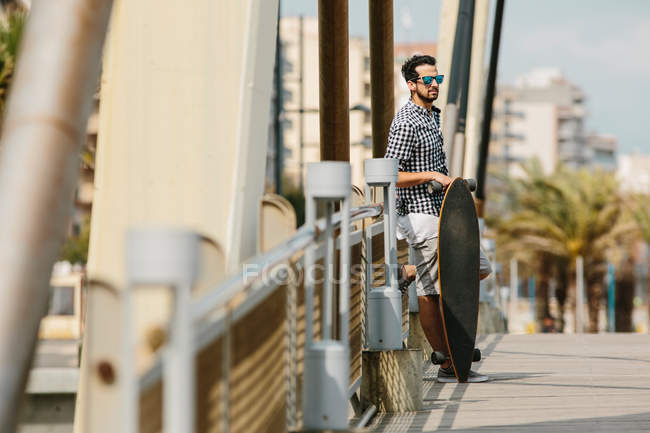 Uomo in piedi con skateboard — Foto stock