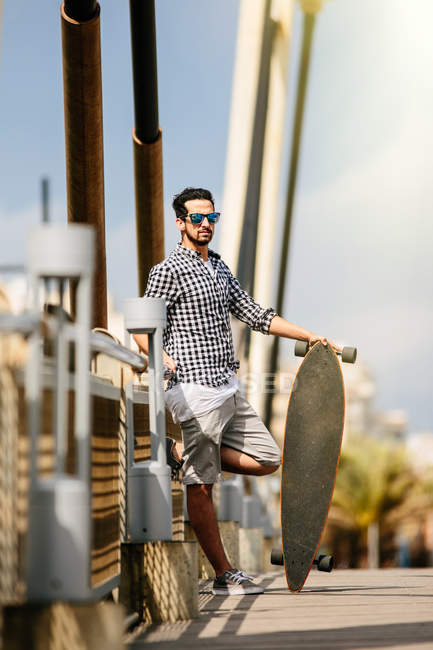 Чоловік стоїть зі скейтбордом — стокове фото