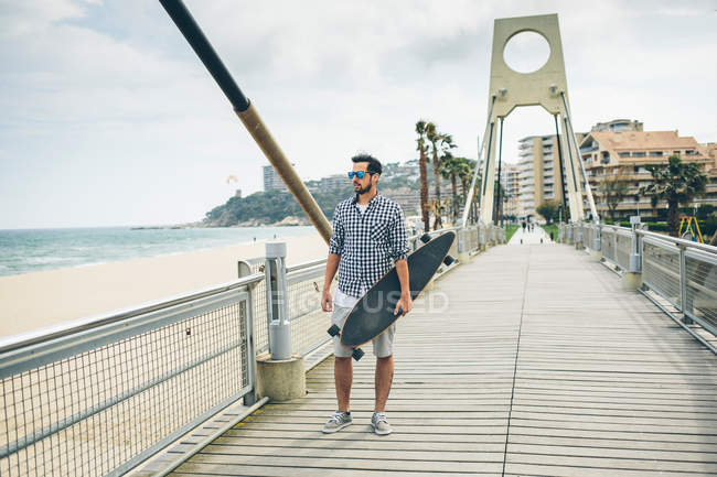 Handsome man walking with skateboard — Stock Photo