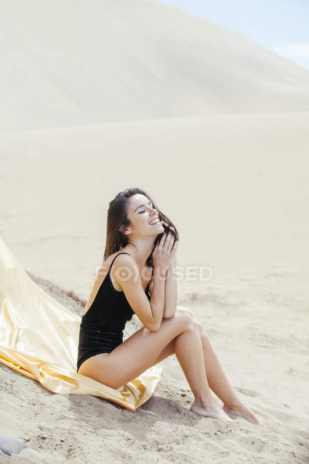 Laughing woman in swimsuit on sand — Stock Photo