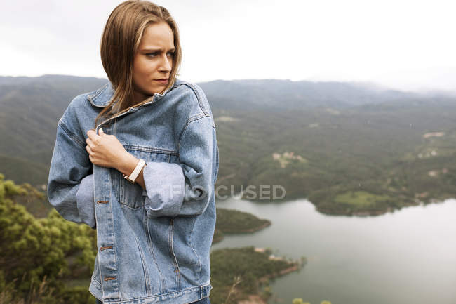 Jeune femme se sentant froid sur la falaise — Photo de stock