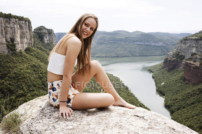 Donna seduta su pietra al bordo — Foto stock
