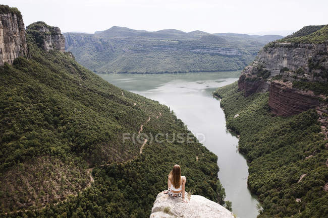 Young woman sitting on edge of cliff — Stock Photo