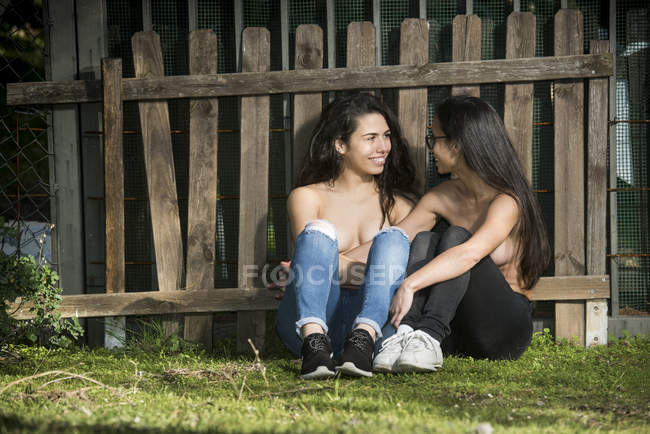 En topless lesbianas pareja cerca de valla - foto de stock