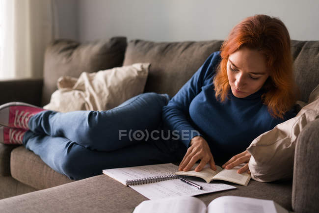 Femme sur canapé avec livre — Photo de stock