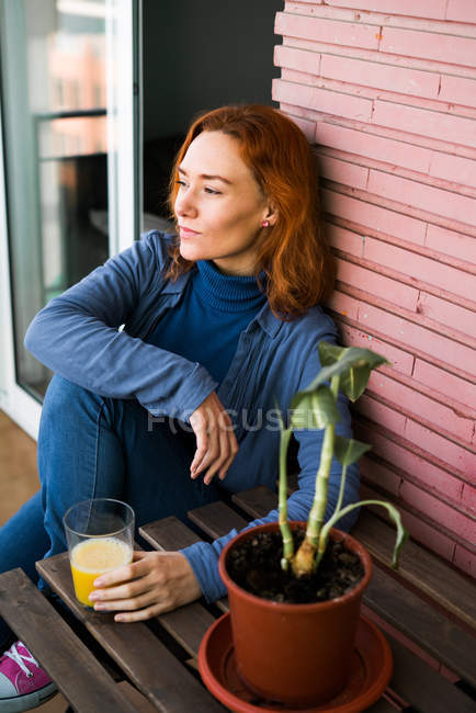 Mujer con jugo en la terraza - foto de stock