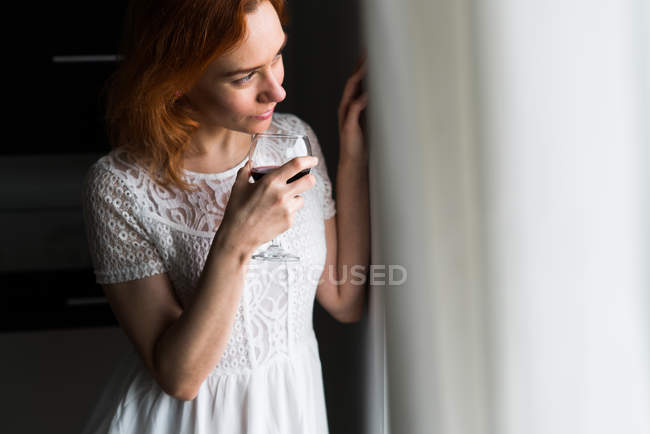 Femme buvant du vin à la fenêtre — Photo de stock