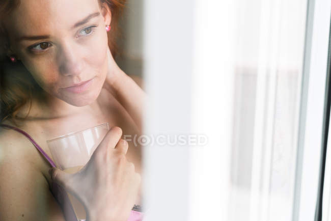 Молода жінка з соком у вікні — стокове фото