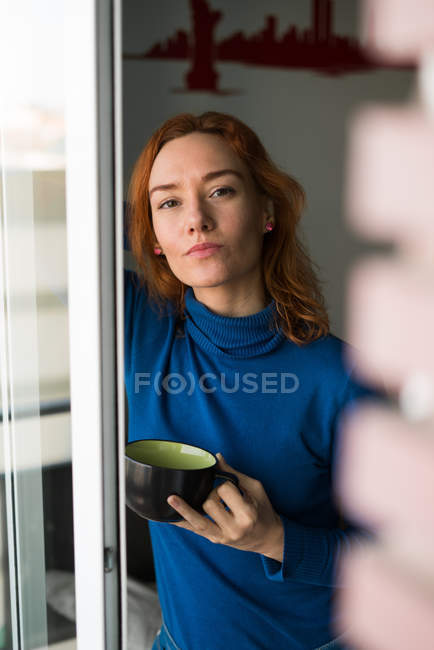 Donna con tazza alla finestra — Foto stock