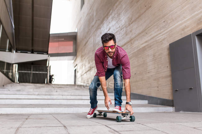 Handsome skateboarder riding on street — Stock Photo