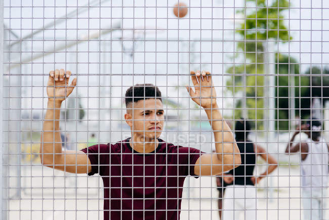 Uomo sportivo posa dietro la recinzione — Foto stock