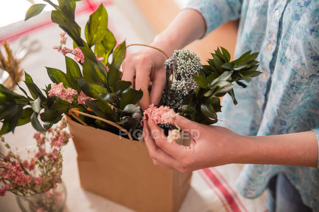 Обрізати людину, що складає квіти в сумці — стокове фото
