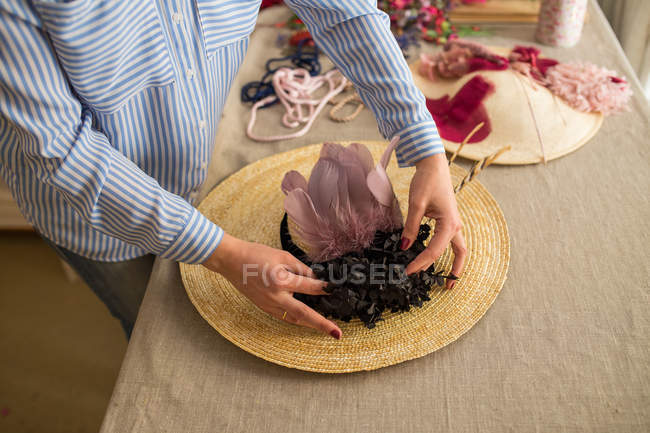 Frau dekoriert Hut mit Blumen — Stockfoto