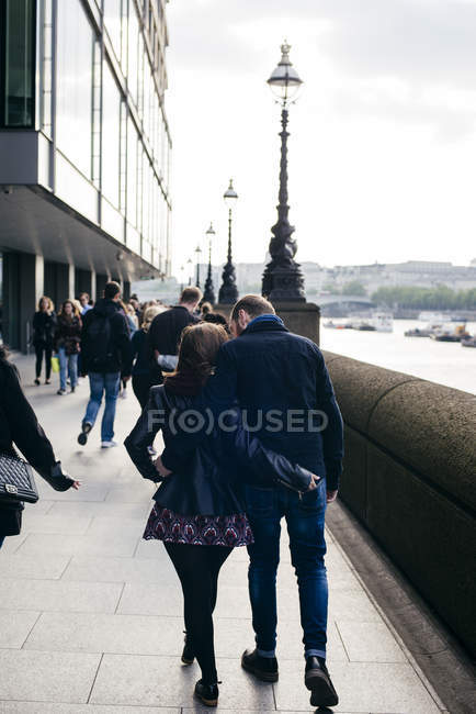 Couple embracing walking on esplanade — Stock Photo
