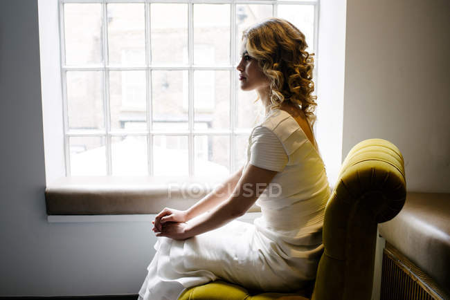 Donna in abito bianco alla finestra — Foto stock