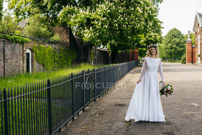 Cheerful woman in gown with bunch — Stock Photo