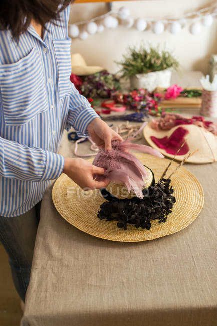 Woman decorating a hat with flowers — Stock Photo