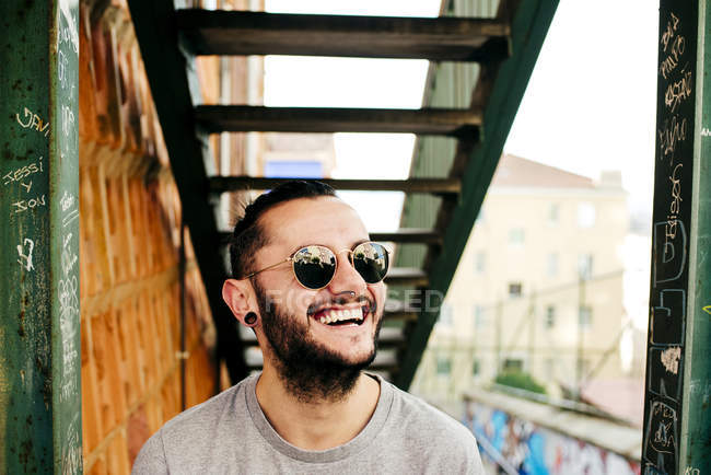 Sonriente hombre hipster en el fondo urbano - foto de stock