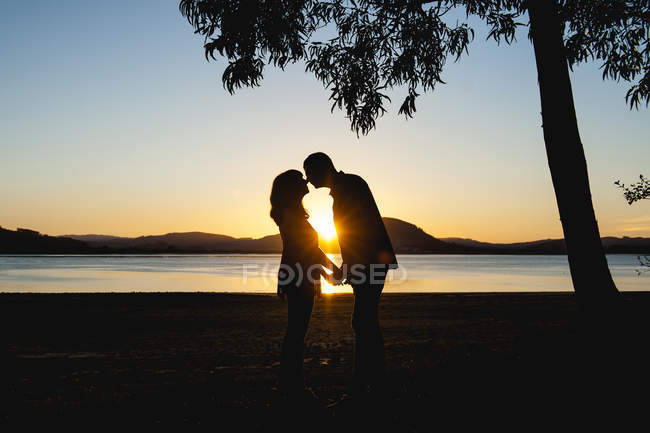 Pareja besándose en la puesta del sol - foto de stock