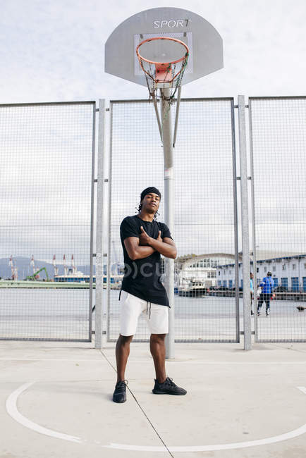 Homem negro confiante posando no chão de basquete — Fotografia de Stock