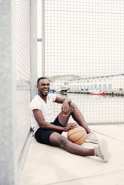 Selbstbewusster Mann sitzt beim Basketball — Stockfoto