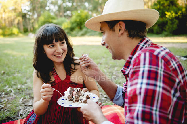 Adult couple having cake on lawn — Stock Photo