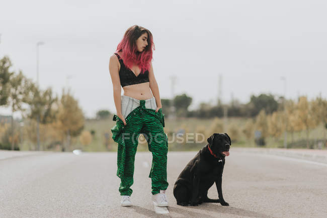 Дівчина з чорною собакою позує на проїжджій частині — стокове фото