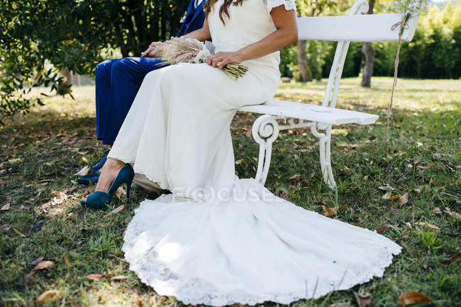 Crop sposa e lo sposo su panchina — Foto stock