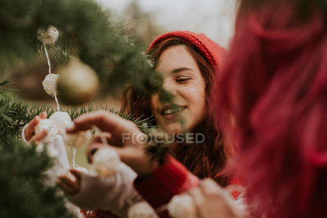 Porträt zweier Mädchen, die Tanne mit Girlanden zu Weihnachten schmücken — Stockfoto
