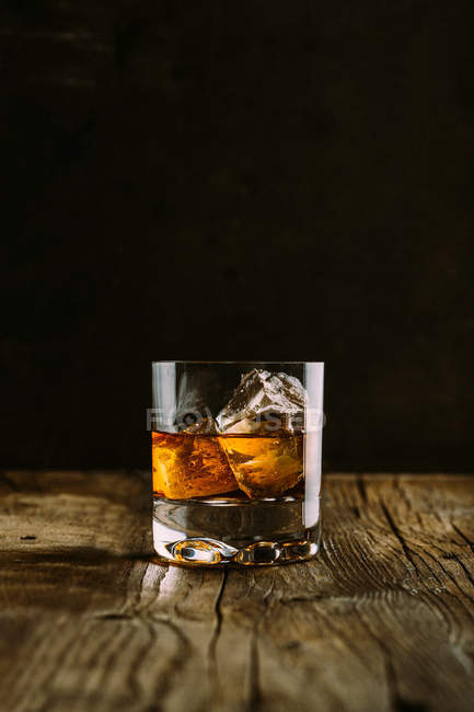 Vaso de whisky sobre mesa de madera - foto de stock