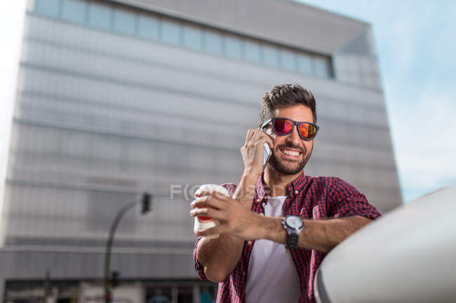 Sonriente hombre con café hablando de teléfono - foto de stock