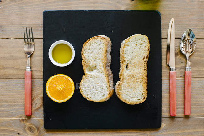 Crunchy toasts with oil and orange — Stock Photo