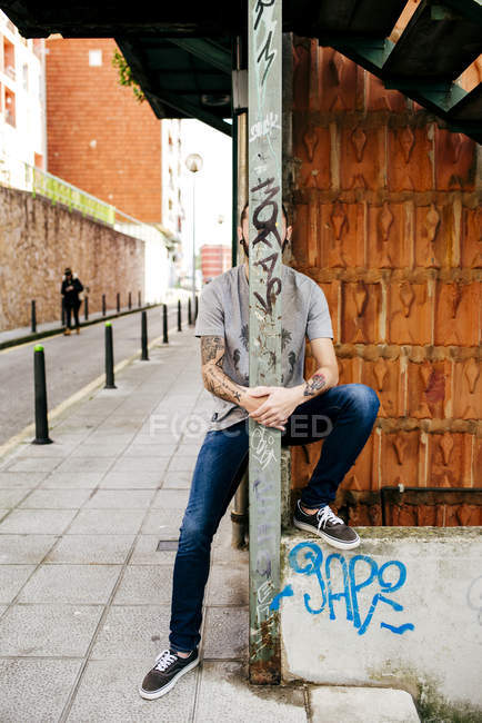 Человек, позирующий за металлическим столбом — стоковое фото