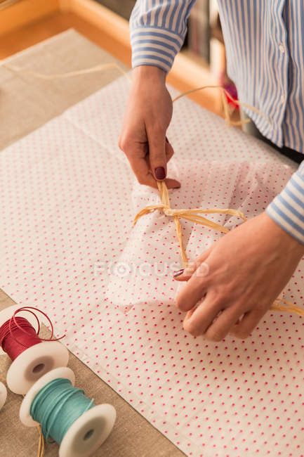 Crop woman twisting ribbon around headwear — Stock Photo