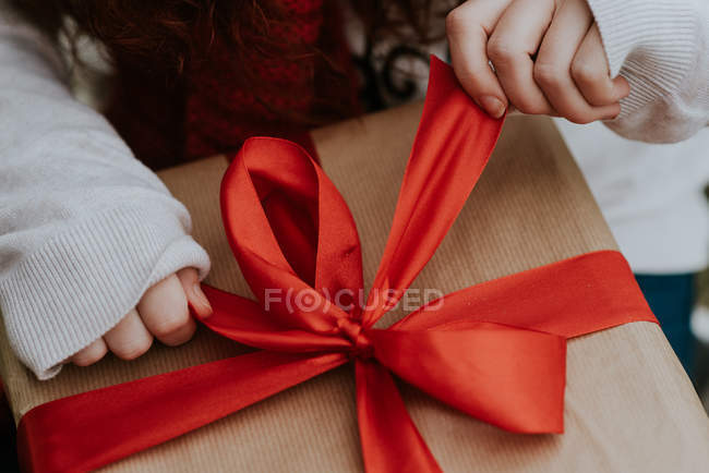 Crop image of girl unwrapping Christmas gift. — Stock Photo