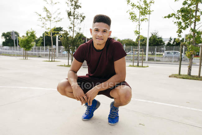 Jeune homme sportif posant dans le squat — Photo de stock