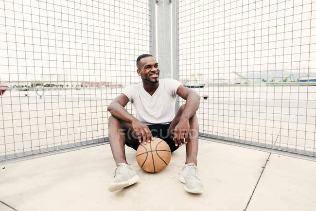 Uomo sicuro seduto con la pallacanestro — Foto stock