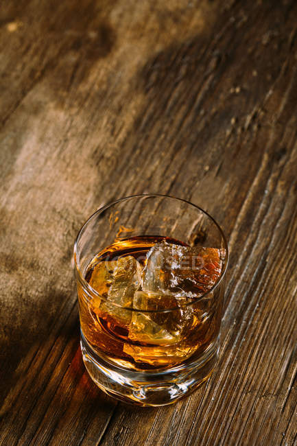 Glass of whiskey on wooden table — Stock Photo