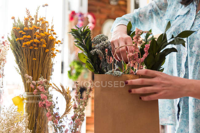 Crop girl composer bouquet dans un sac en papier — Photo de stock
