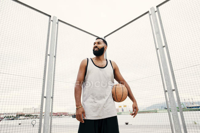Уверенный человек позирует с баскетболом — стоковое фото