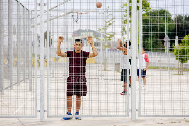 Sportlicher junger Mann posiert hinter dem Zaun — Stockfoto