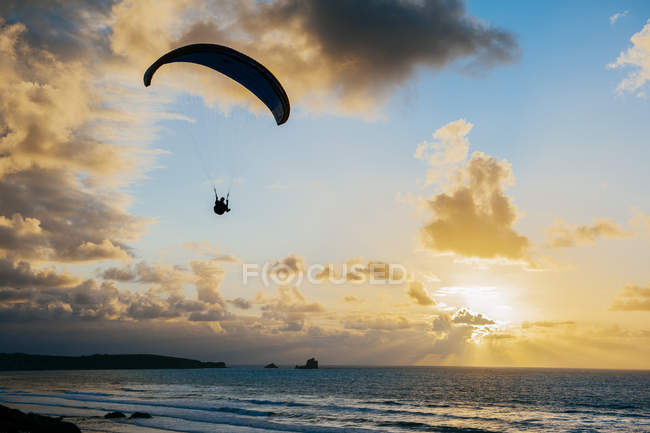 Silhouette flying on parachute over sea — Stock Photo