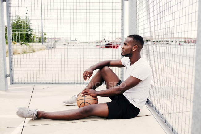 Hombre seguro sentado con baloncesto - foto de stock