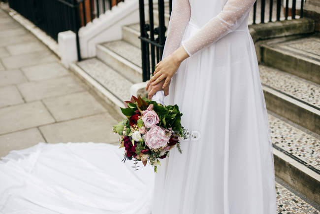 Unerkennbare Frau mit Blumen im weißen Kleid — Stockfoto