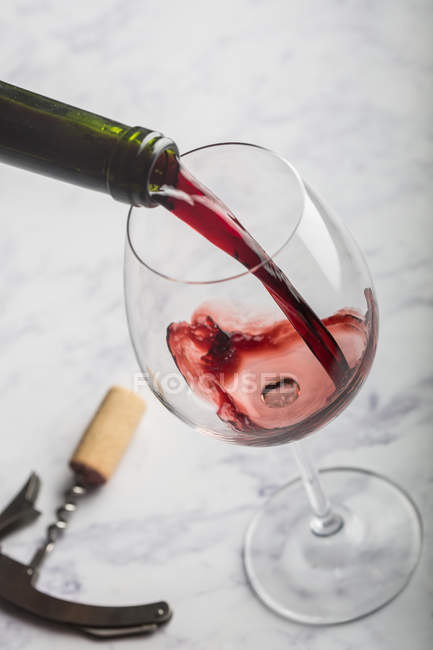 Подача червоного вина в склянці на мармуровому столі — стокове фото