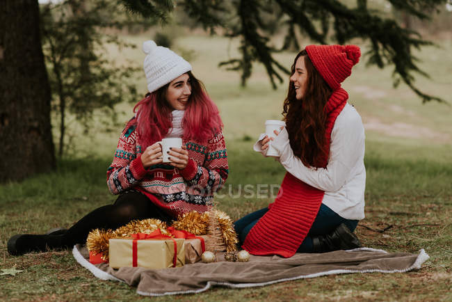 Two teen girlfriends sitting on festive picnic in forest — Stock Photo