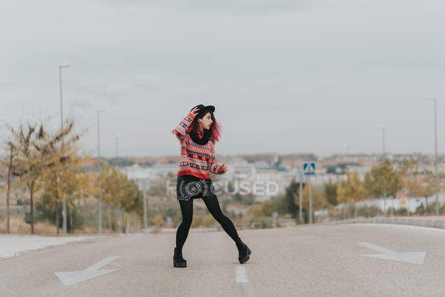 Дівчина з капелюхом позує на міській дорозі — стокове фото