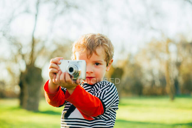 Criança no campo tirando uma foto com uma câmera compacta — Fotografia de Stock