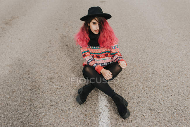 Ragazza in cappello nero seduta su strada — Foto stock